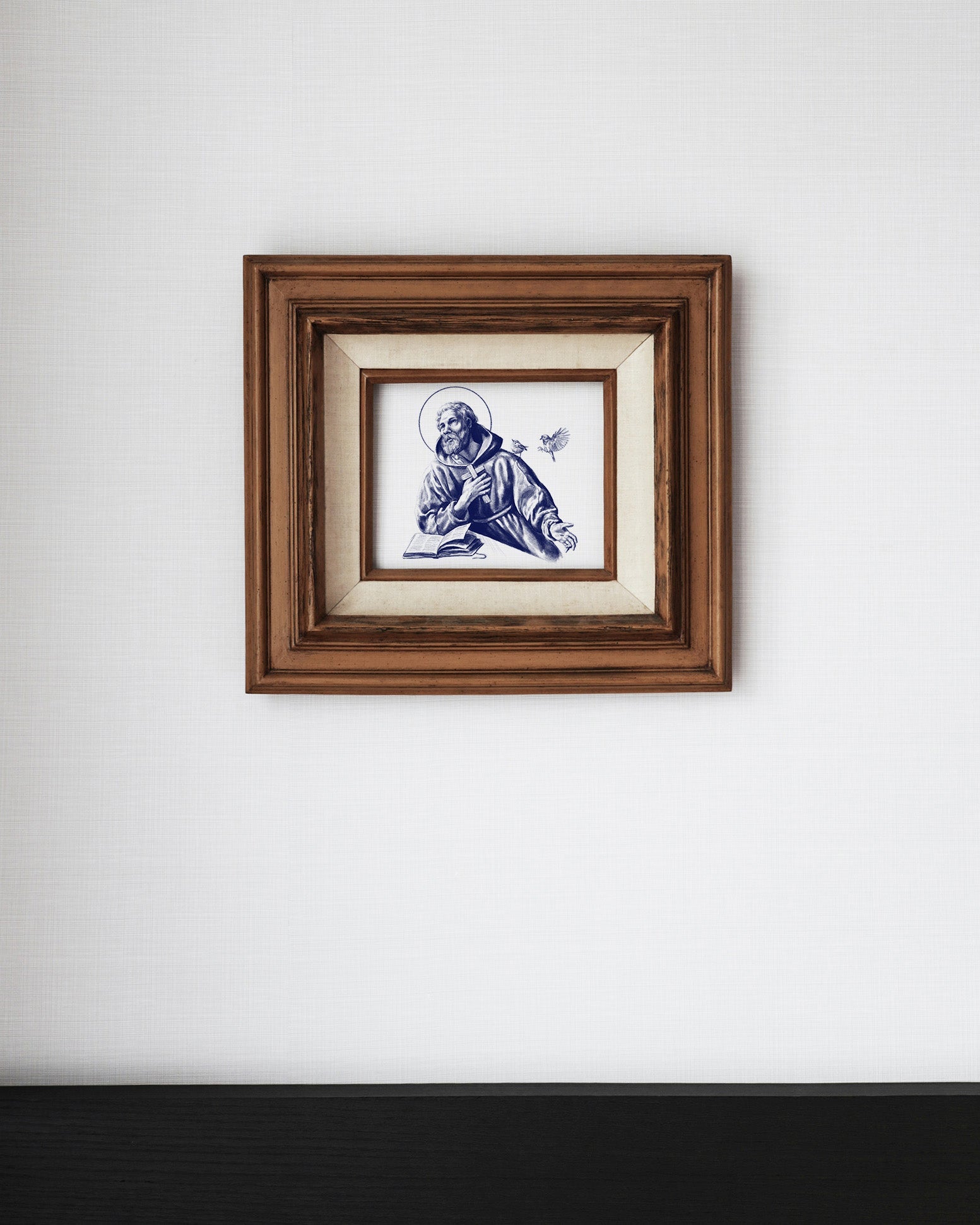 dessin bleu de Saint François d'Assise dans un cadre en bois sur un mur blanc